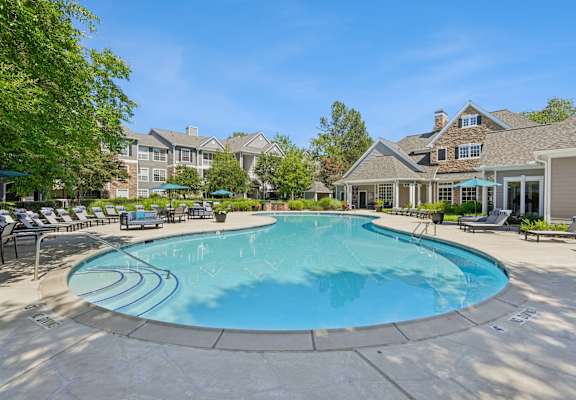 A large swimming pool surrounded by lounge chairs and umbrellas.