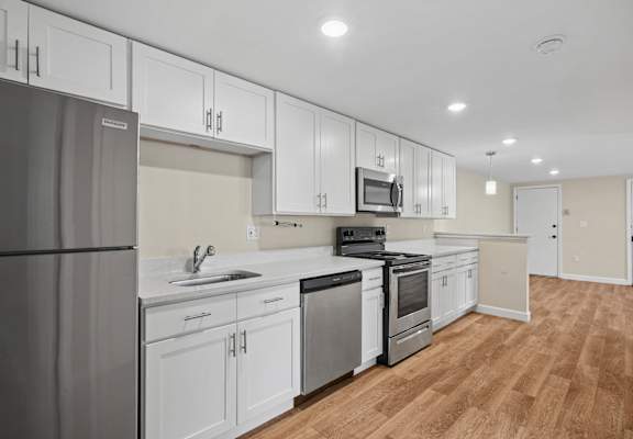 A modern kitchen with white cabinets and stainless steel appliances.