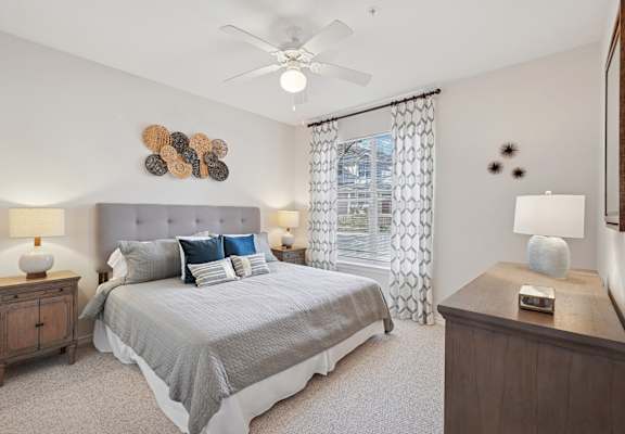 A bedroom with a bed, nightstands, and a ceiling fan.