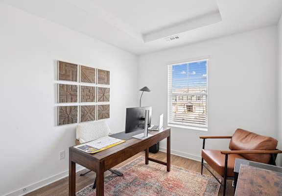 A room with a desk, chair, and pictures on the wall.