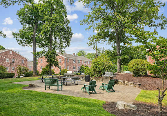 A green park area with a table and chairs in front of a building.