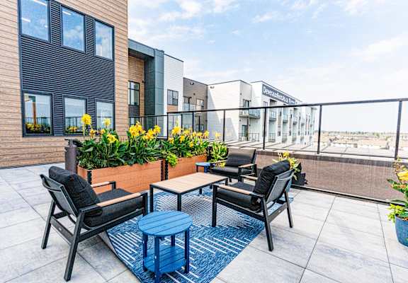 A patio with a table and chairs overlooking a building. at Vista Apartments at Edgemont, Edmonton, AB