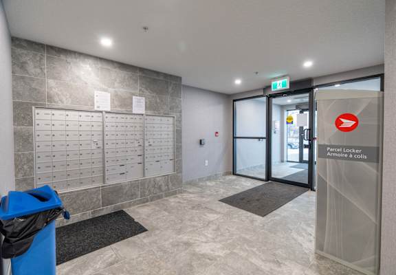 A hallway with a blue trash can and a sign for a parcel locker.