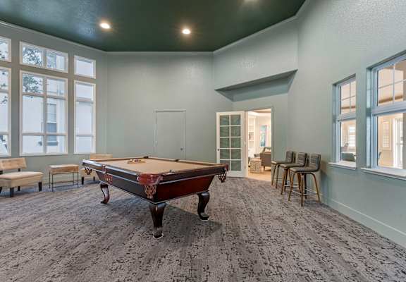A pool table is in the middle of a room with a carpeted floor.