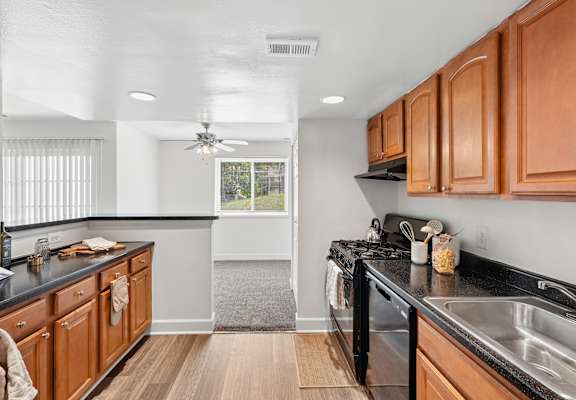 A kitchen with wooden cabinets and black countertops.