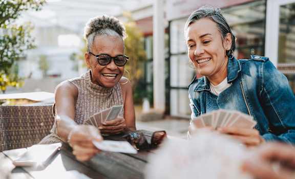 Two women are sitting at a table playing cards.