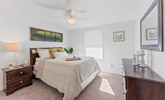 a bedroom with a bed and a dresser and a ceiling fan
