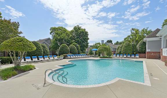 A large swimming pool surrounded by trees and lounge chairs.