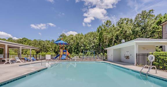 A large swimming pool with a slide and a house in the background.