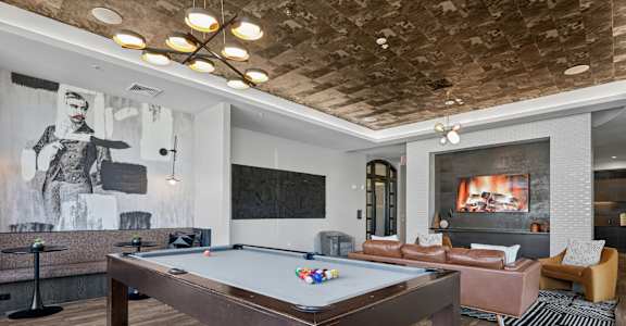 A pool table is in the middle of a room with a fireplace and a couch.