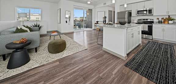 A modern kitchen with white cabinets and a wooden floor.