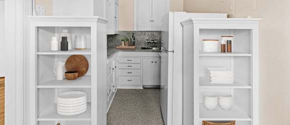 A kitchen with white cabinets and a countertop with a sink.