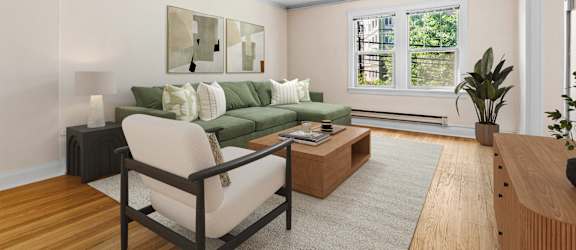 A living room with a green couch, a chair, a coffee table, and a painting on the wall.