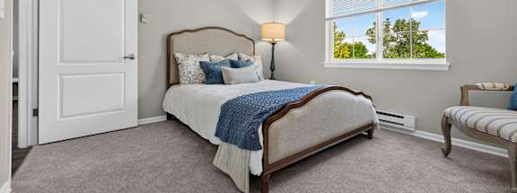 A bedroom with a large bed and a window overlooking a tree.