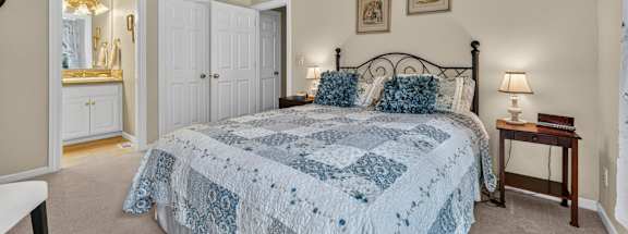 A bedroom with a bed, nightstand, and a ceiling fan.