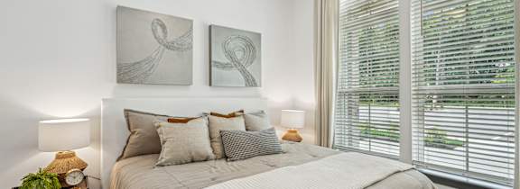 a bedroom with white walls and a bed with green blankets and pillows at The Leo Myrtle Beach, South Carolina, 29579