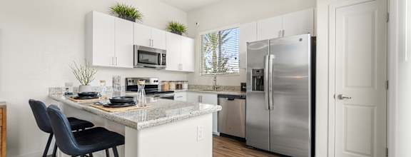 a walk in closet with white cabinets and a mirror