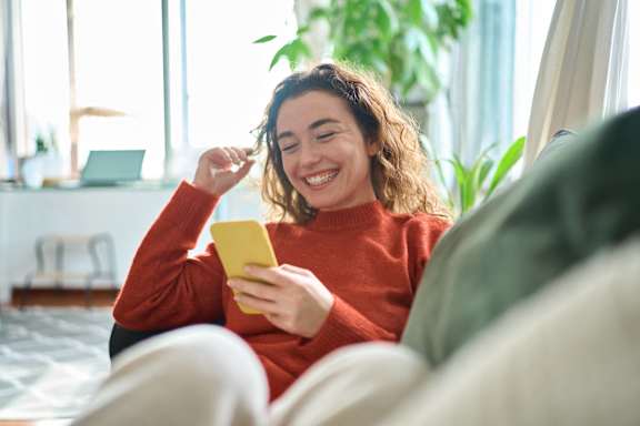 a woman sitting on a couch looking at her cell phone