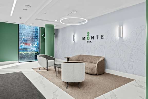 A modern waiting room with a green wall and a white couch.
