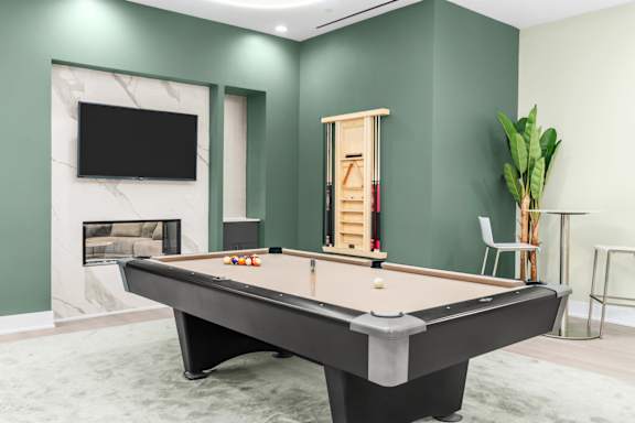 A pool table is in the middle of a room with a TV and a fireplace.