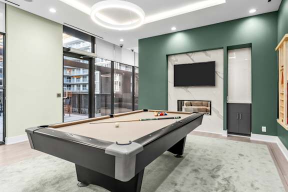 A pool table is in the middle of a room with a television and a fireplace.
