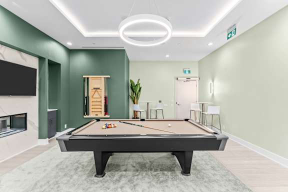 A pool table is in the middle of a room with green walls.