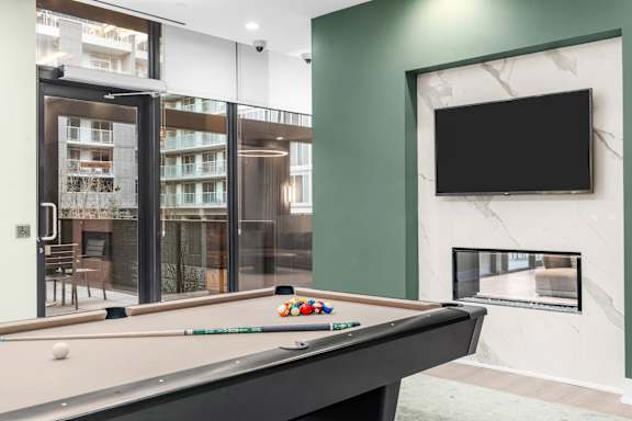 A pool table with a green wall and a television mounted on it.