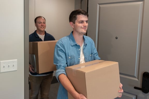 a man holding a box and another man carrying a box in a room