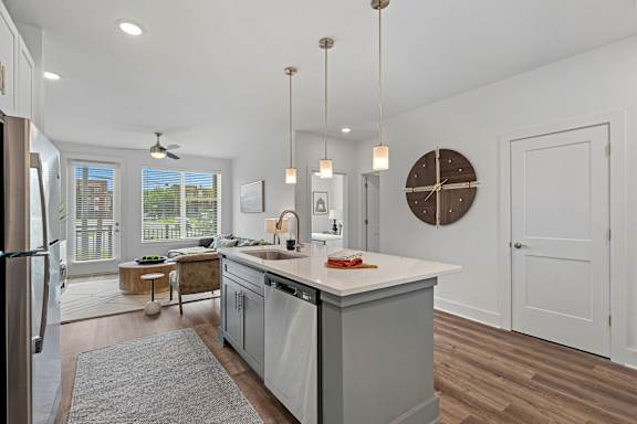 A modern kitchen with a large island and pendant lights.