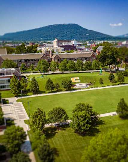 A view of a campus with a green field and buildings.