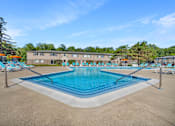 Thumbnail 6 of 9 - A large swimming pool with lounge chairs and a building in the background.