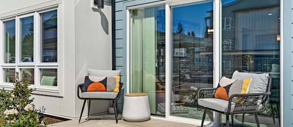 a patio with two chairs and a table outside a house