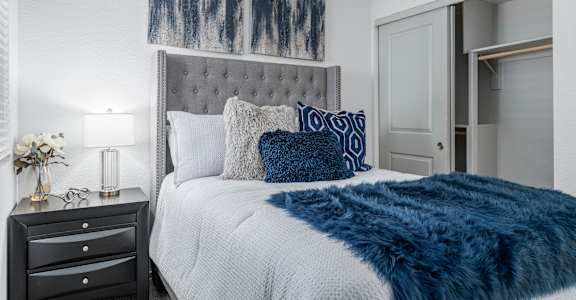 A bedroom with a bed, nightstand, and a painting on the wall.