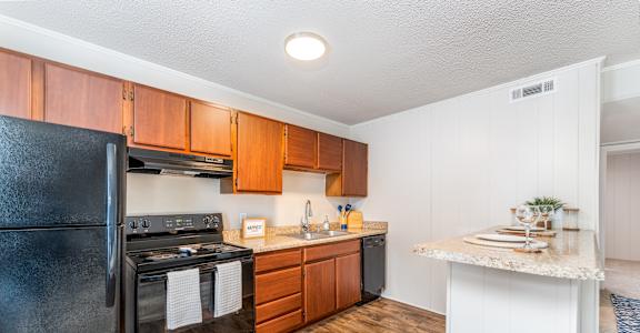 A black stove and oven in a kitchen with wooden floors and white walls.