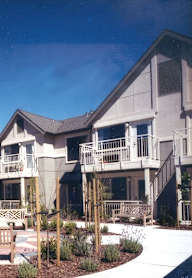 A large house with a balcony and a small garden in front.