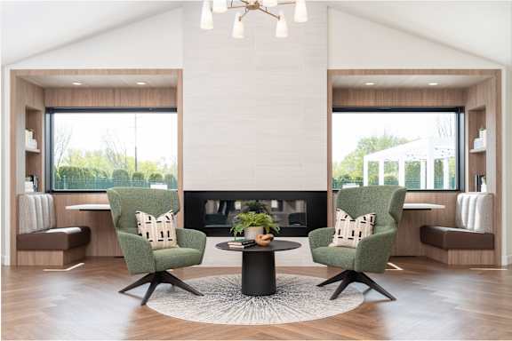 A modern living room with a fireplace and two green chairs.