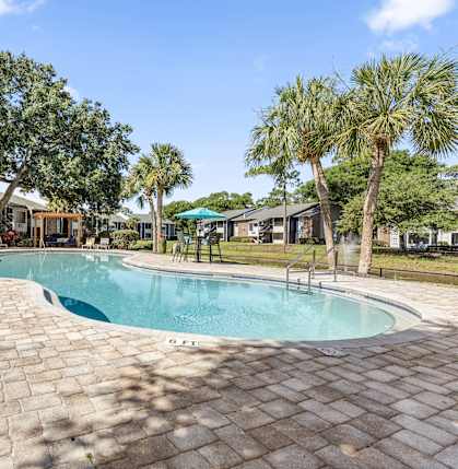 a resort style swimming pool with trees and buildings in the background