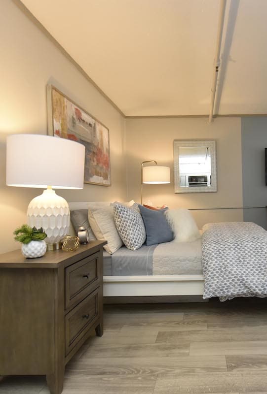 a bedroom with a bed and a dresser with a lamp