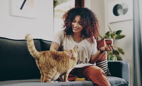 a woman sitting on a couch with her cat and holding a cup of coffee