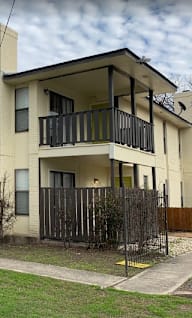 A two-story apartment building with a balcony on the second floor.