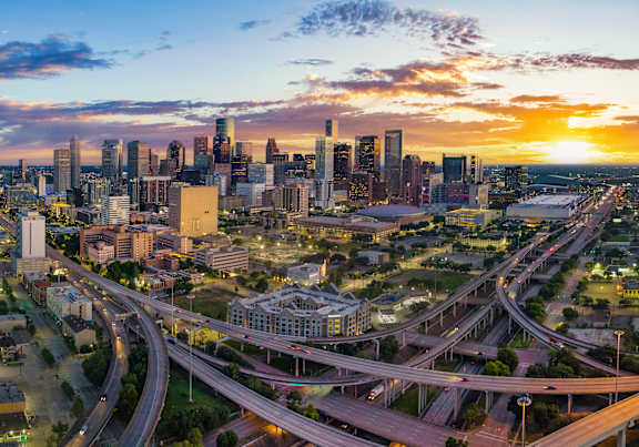 A cityscape with a sunset in the background and a busy highway.