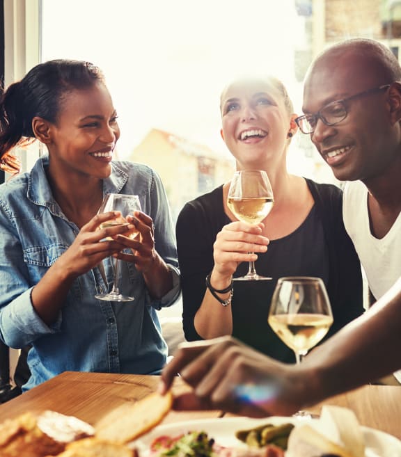 three people drinking wine and eating at a restaurant at Allure Apollo, Camp Springs