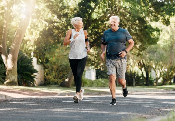 an older man and woman running down a street