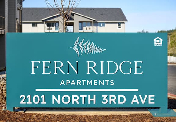 a sign for fern ridge apartments in front of a house