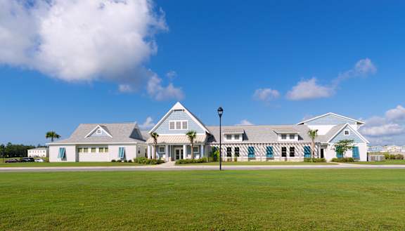 A large white building with a triangular roof and a green lawn in front.