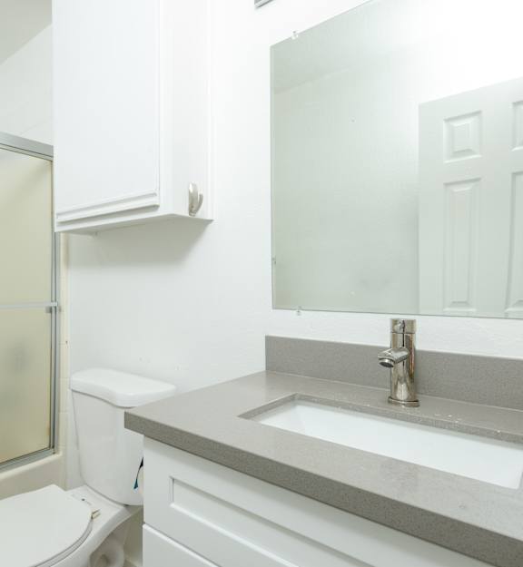 A bathroom with a toilet, sink, and frosted glass shower door.
