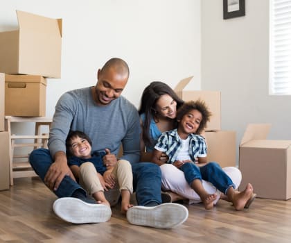 a family sitting on the floor in their new home with cardboard boxes