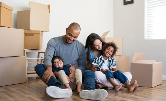 a family sitting on the floor in their new home with cardboard boxes