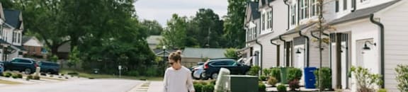 A woman walking her dog on a suburban street.