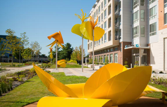 a large yellow sculpture in a park in front of an apartment building at The Metropolitan Downtown Columbia, Columbia, MD, 21044